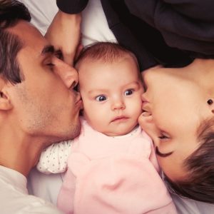 Mother and father with little baby in a bed