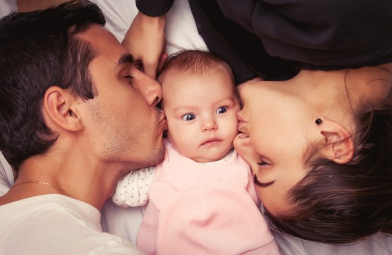 Mother and father with little baby in a bed